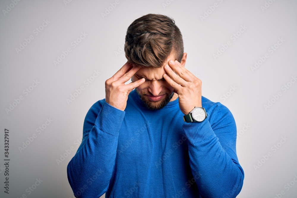 Young handsome blond man with beard and blue eyes wearing casual sweater with hand on head for pain in head because stress. Suffering migraine. Young handsome blond man with beard and blue eyes wearing casual sweater with hand on head for pain in head because stress. Suffering migraine.