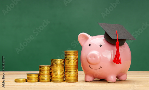 Foto Piggy bank in a graduate cap near a stack of coins