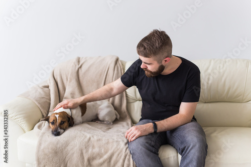 Man with cute dog jack russell terrier on the couch. Pets and home concept.