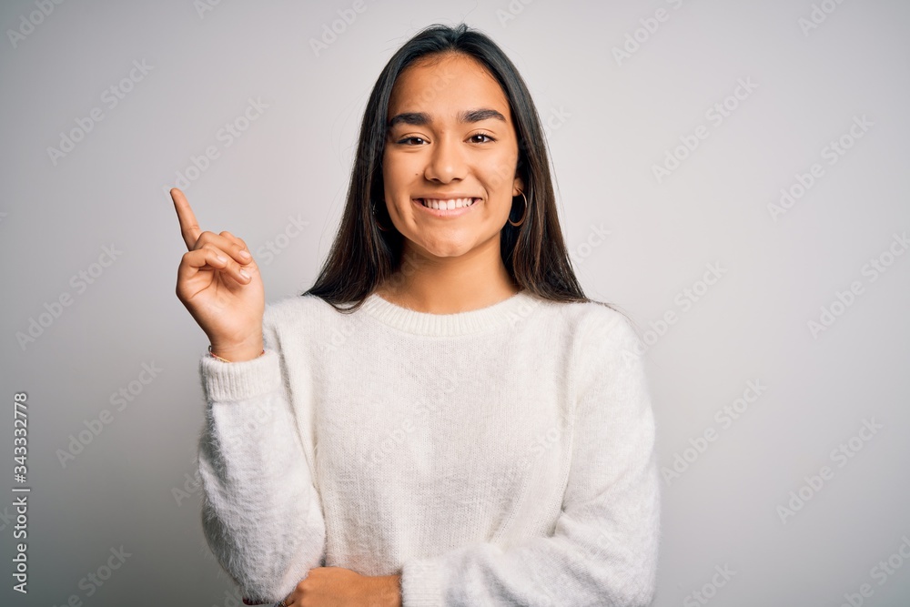 Young beautiful asian woman wearing casual sweater standing over white background with a big smile on face, pointing with hand and finger to the side looking at the camera. Young beautiful asian woman wearing casual sweater standing over white background with a big smile on face, pointing with hand and finger to the side looking at the camera.