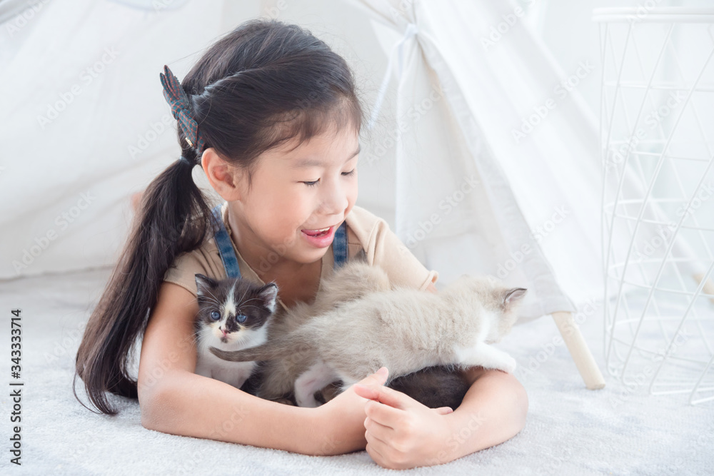 Little asian girl lying on the floor and playing with her little kitten happily. Little asian girl lying on the floor and playing with her little kitten happily.