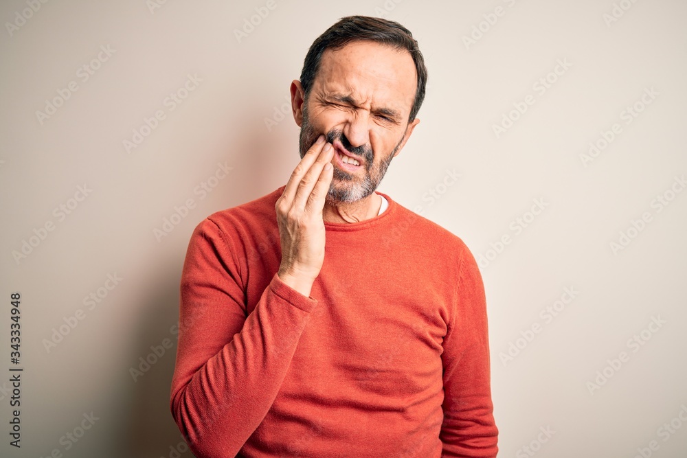 Middle age hoary man wearing casual orange sweater standing over isolated white background touching mouth with hand with painful expression because of toothache or dental illness on teeth. Dentist Middle age hoary man wearing casual orange sweater standing over isolated white background touching mouth with hand with painful expression because of toothache or dental illness on teeth. Dentist