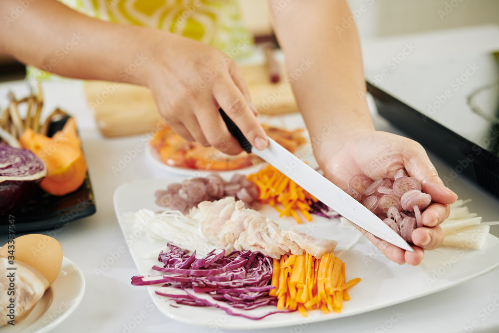 Close-up image of woman cutting ingredients for delicious dish