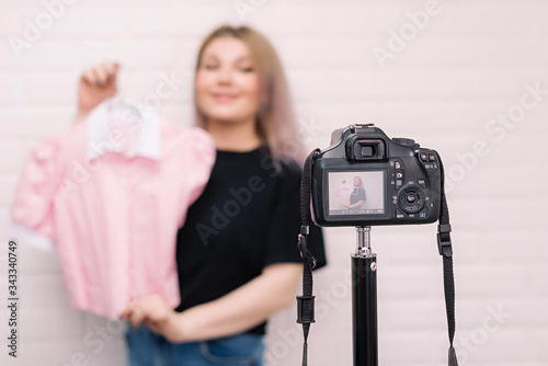 .A stylist blogger holds a blouse in front of the camera.