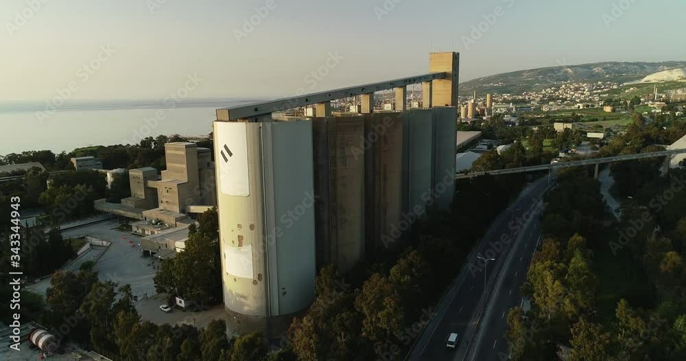 Aerial circle shot of factory silos and surrounding city limits on sunny day Aerial circle shot of factory silos and surrounding city limits on sunny day