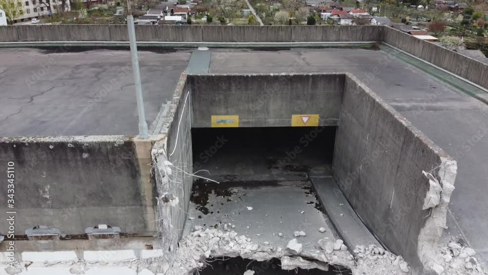 Descent of a drone closely facing a old demolished parking garage with local gardens in the back of building Descent of a drone closely facing a old demolished parking garage with local gardens in the back of building