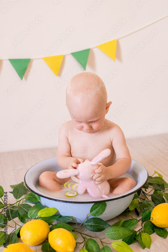 Cute toddler boy with blond hair sitting in a basin with milk and lemons in a bright studio. Healthy childhood Cute toddler boy with blond hair sitting in a basin with milk and lemons in a bright studio. Healthy childhood