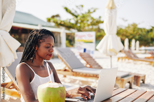 Concentrated female blogger sitting at table on beach and working on article or blog post photo