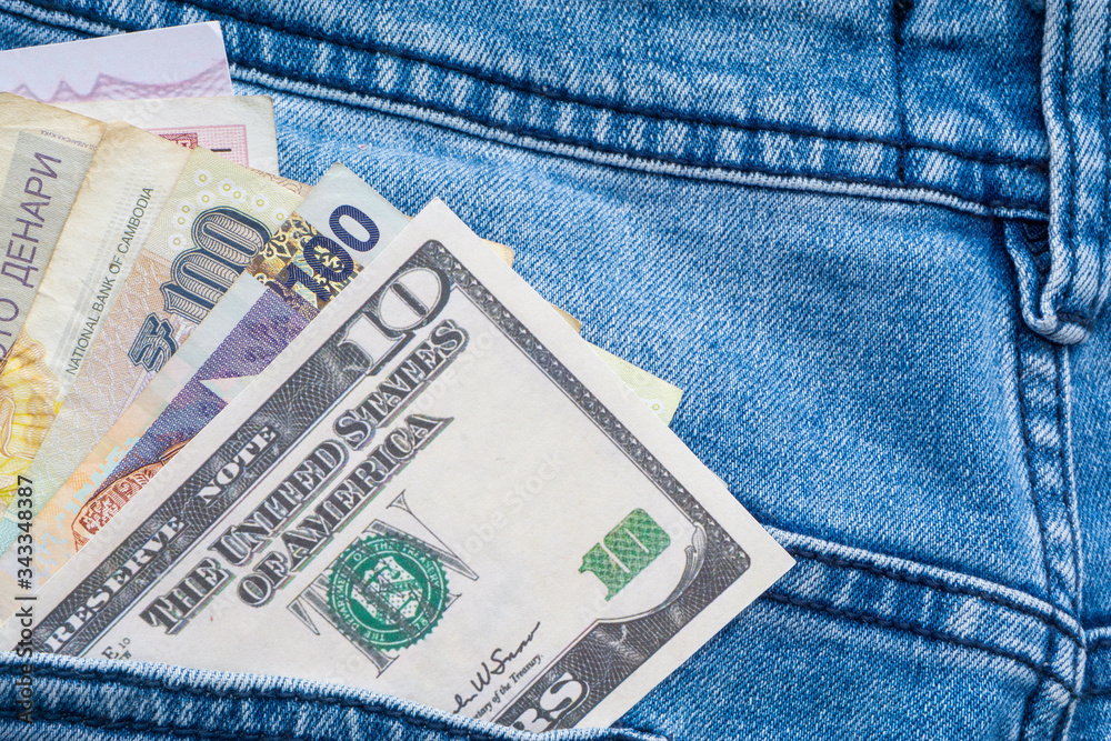 Multi currency banknotes in back pocket of blue jeans. Business concept Multi currency banknotes in back pocket of blue jeans. Business concept