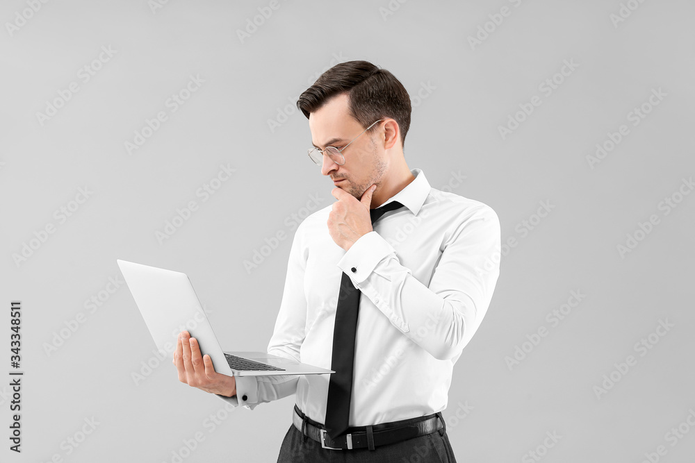 Portrait of handsome businessman with laptop on grey background Portrait of handsome businessman with laptop on grey background