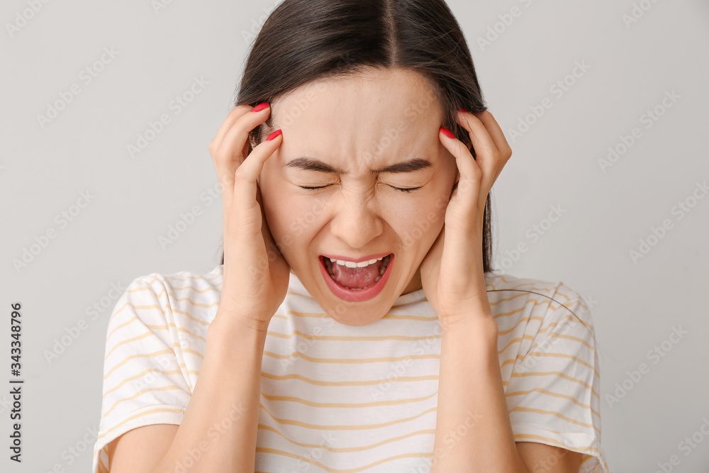 Portrait of screaming young woman on grey background Portrait of screaming young woman on grey background