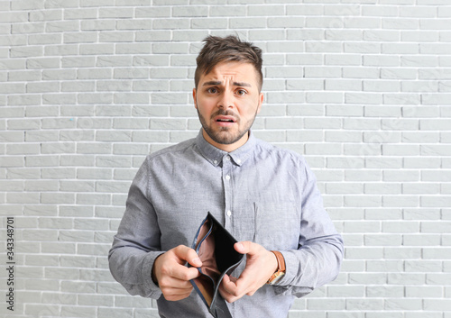 Sad man with empty purse on...