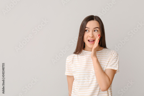 Portrait of emotional young woman on grey background