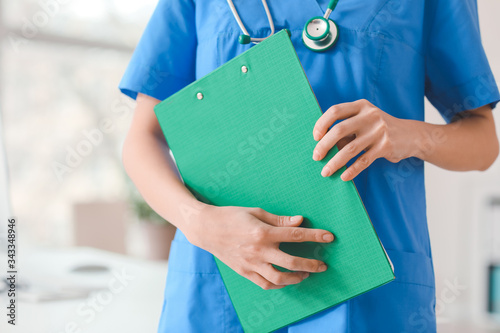 Female doctor with clipboard in clinic, closeup