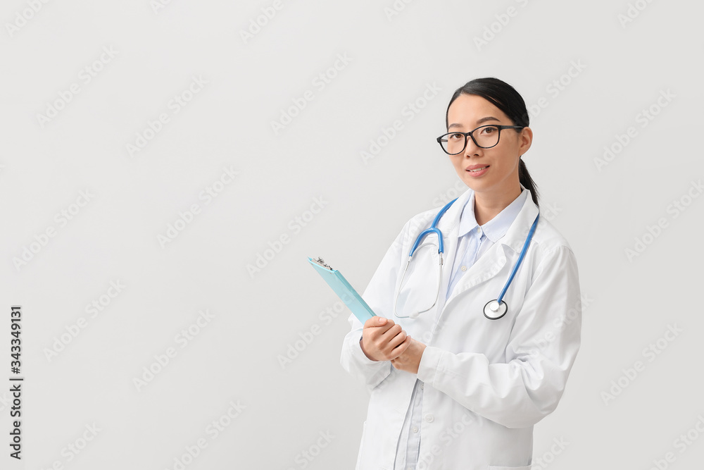 Female Asian doctor on light background