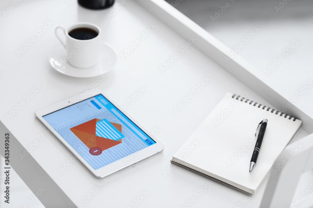 Tablet computer with open e-mail box on screen, notebook and cup of coffee on table Tablet computer with open e-mail box on screen, notebook and cup of coffee on table