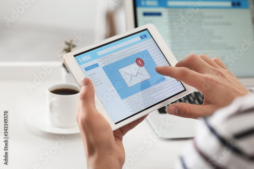 Young man with tablet computer checking his e-mail at home