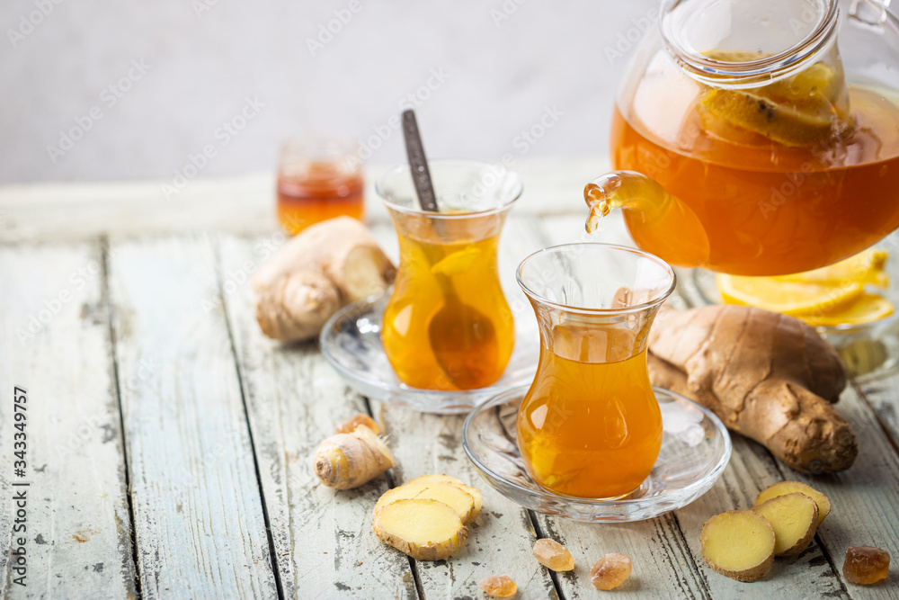 Ginger tea in a glass cup with lemon and mint on light background Ginger tea in a glass cup with lemon and mint on light background