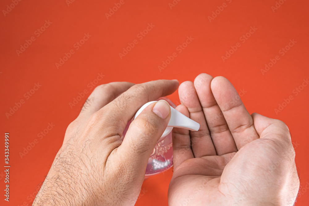 Man hand in container with alcohol gel on the red background Man hand in container with alcohol gel on the red background