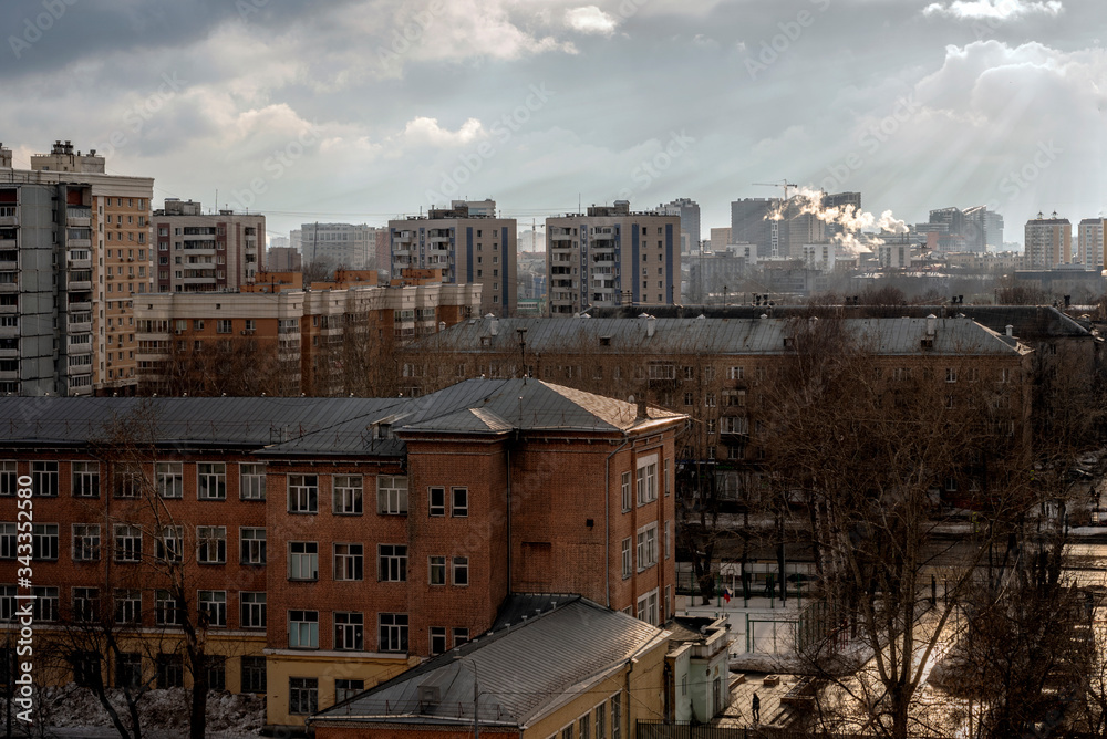 Cityscape in the rays of the setting sun in a cloudy sky