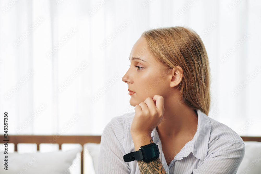Pensive pretty young woman with smartwatch on her wrist looking away Pensive pretty young woman with smartwatch on her wrist looking away