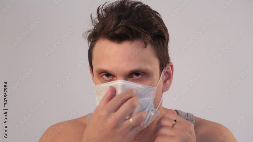 Portrait of a man on a white background in a medical mask. Demonstration of medical equipment. The patient coughs. The concept of quarantine, self-isolation, protection from coronavirus, virus, fear o Portrait of a man on a white background in a medical mask. Demonstration of medical equipment. The patient coughs. The concept of quarantine, self-isolation, protection from coronavirus, virus, fear o