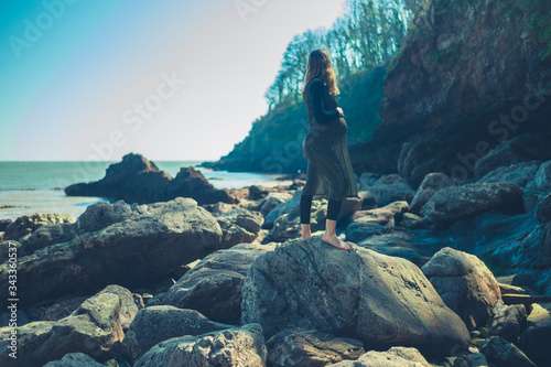 Pregnant woman walking on rock by the sea