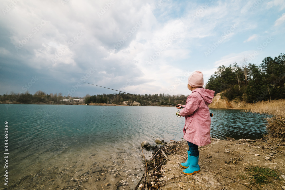 Little girl catching a fish. Lonely happy little child fishing from beach lake or pond with text space. Photo of children pulling rod while fishing on the weekend. Little girl catching a fish. Lonely happy little child fishing from beach lake or pond with text space. Photo of children pulling rod while fishing on the weekend.