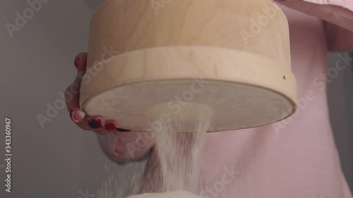 Slow motion, a woman sifting flour through a sieve. Side view, close-up.