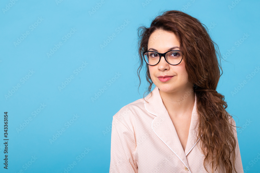 Smiling young girl in pajamas home wear posing while resting at home isolated on blue background with copy space studio portrait. Relax good mood lifestyle concept. Smiling young girl in pajamas home wear posing while resting at home isolated on blue background with copy space studio portrait. Relax good mood lifestyle concept.