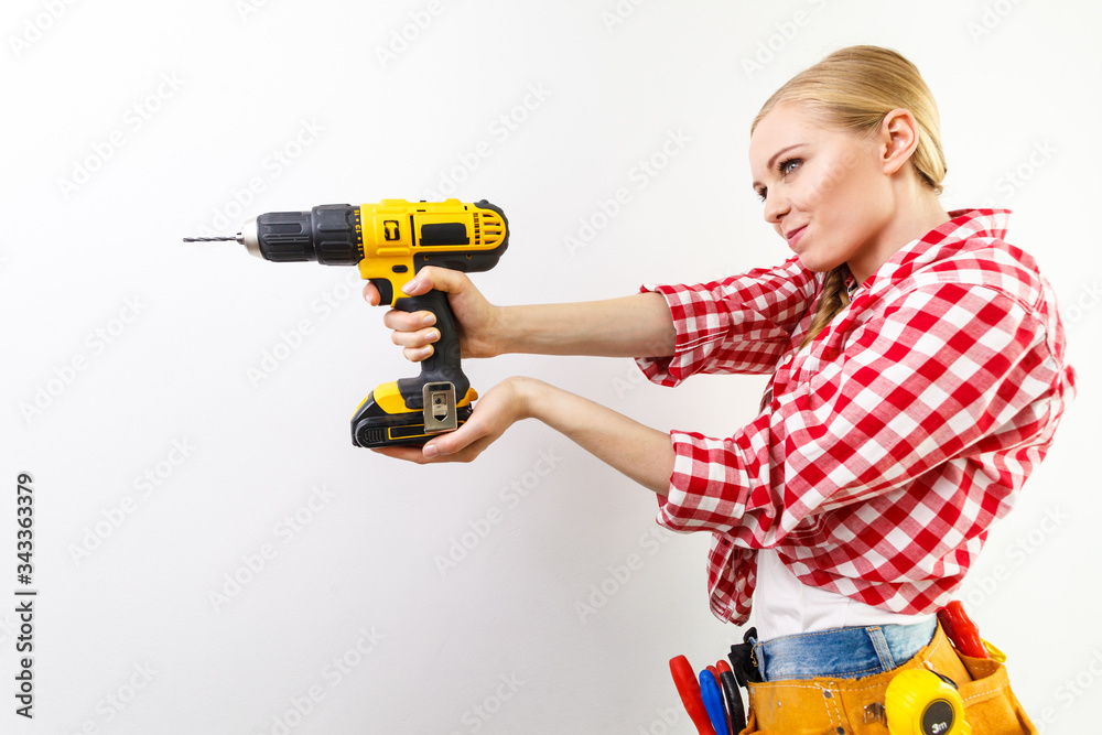 Woman using drill on wall Woman using drill on wall