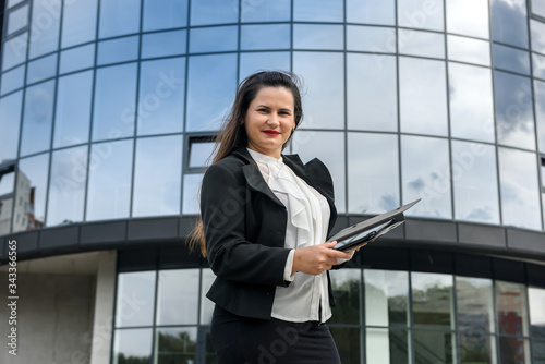 Portrait of beautiful woman with tablet outdoors near big office center