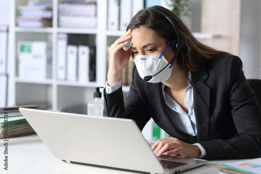 Worried telemarketer with mask looking at laptop Worried telemarketer with mask looking at laptop