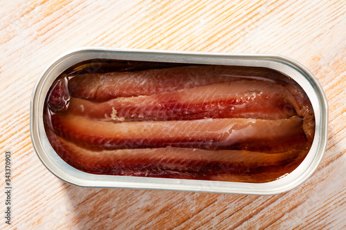 Close-up of canned anchovy fillet in oil on wooden surface