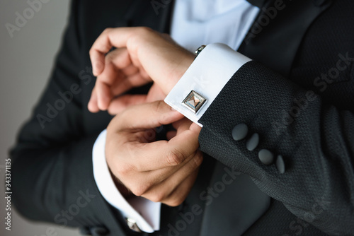 Businessman adjusts his white shirt button .