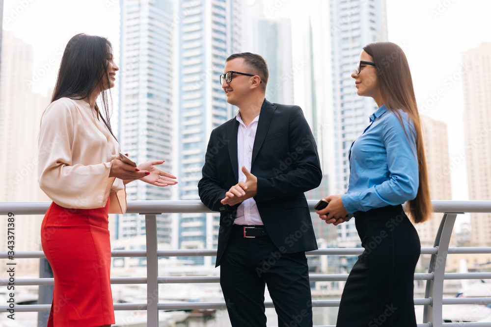 Businessman and two woman discussing about a meeting in the city. Three business people talking at business center outdoor. Businessman and two woman discussing about a meeting in the city. Three business people talking at business center outdoor.