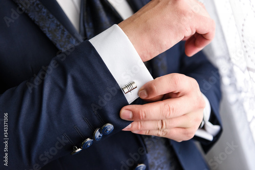 Businessman adjusts his white shirt button .