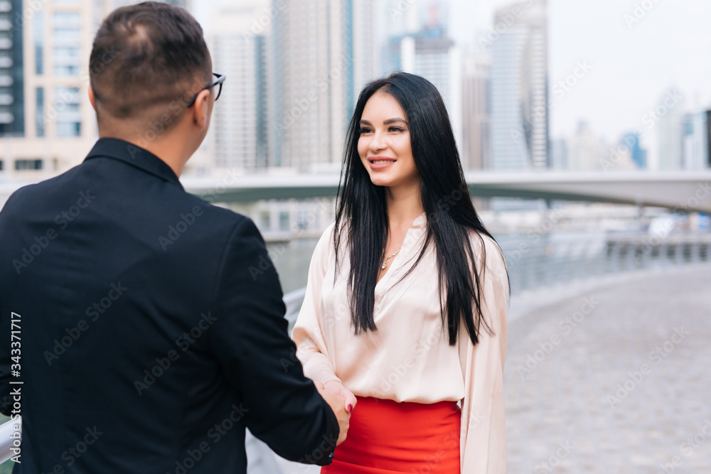 Young business people shaking hands with skyscrapers city background Young business people shaking hands with skyscrapers city background