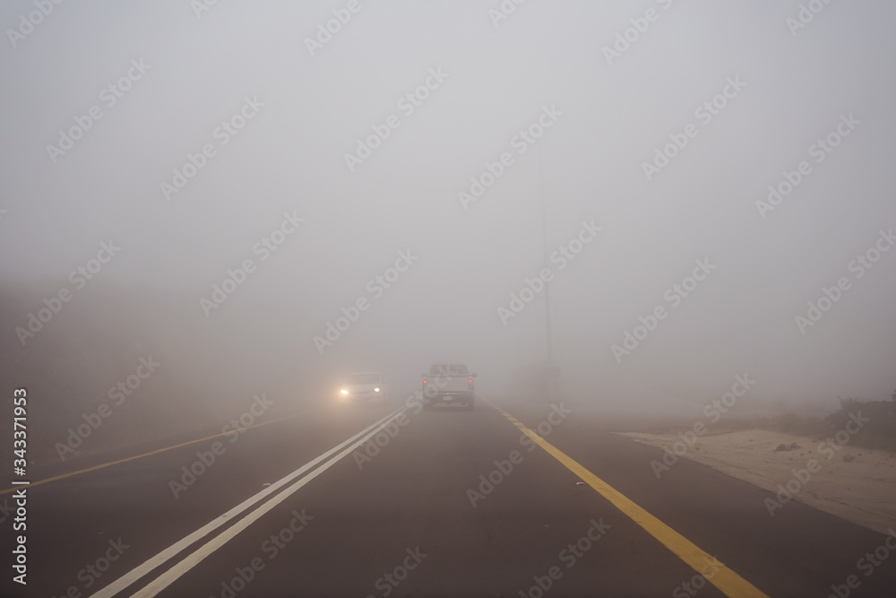 Car and truck driving in dense fog in the mountains near Abha