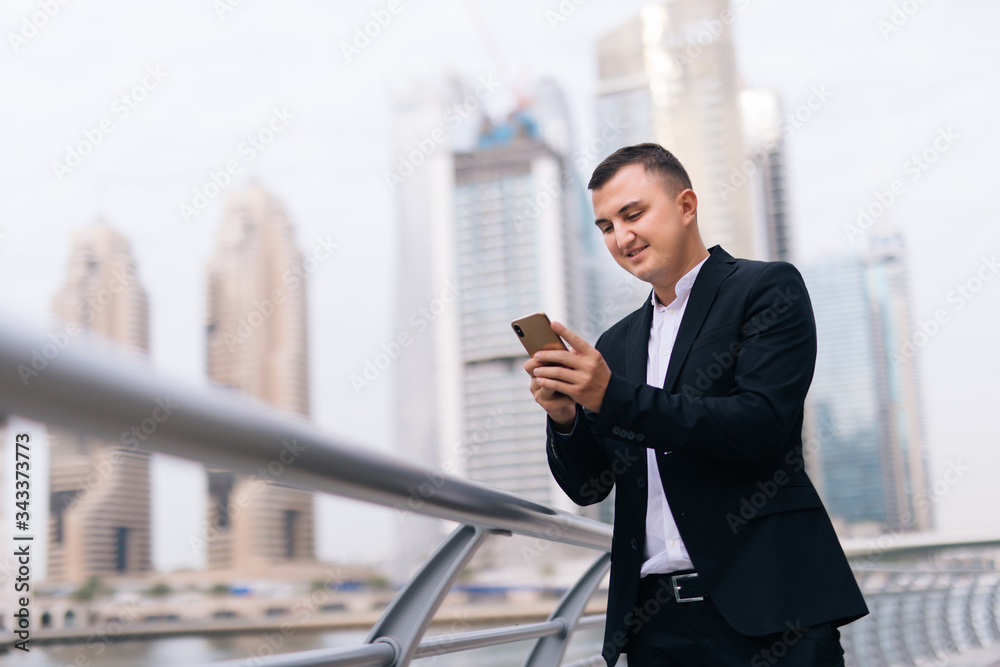 Young handsome businessman reading text message on cell phone on skyscrapers background Young handsome businessman reading text message on cell phone on skyscrapers background