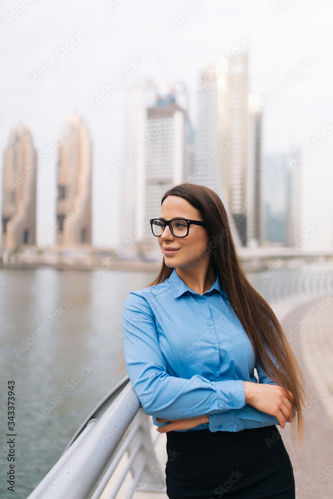 Fototapeta premium Portrait of a successful business woman in glasses smiling in an urban setting