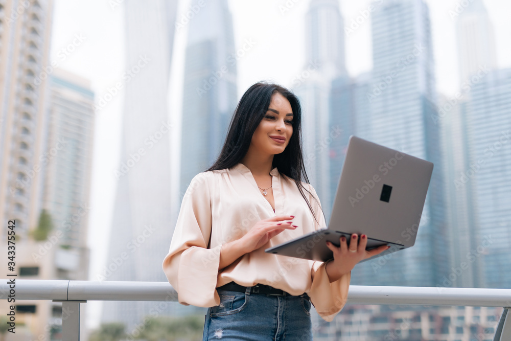 Young attractive businesswoman with laptop over city skyscrapers background Young attractive businesswoman with laptop over city skyscrapers background