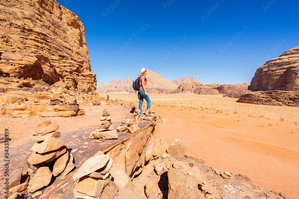 Woman with backpack and hat looking on desert from rock. Wadi Rum, Jordan. Travel and tourism concept. Woman with backpack and hat looking on desert from rock. Wadi Rum, Jordan. Travel and tourism concept.