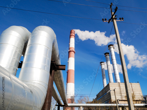 Plant, factory, with smoking chimneys against the blue sky.
