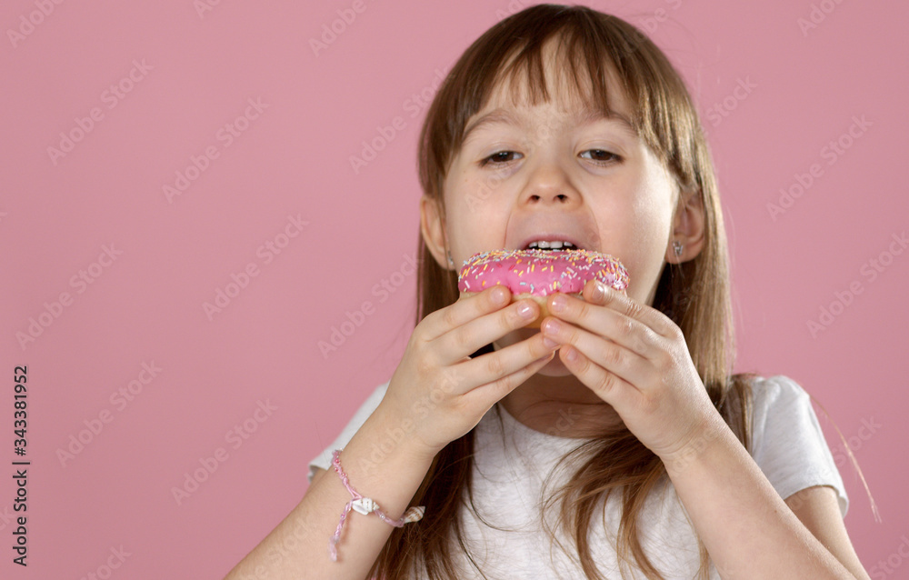 Cute young caucasian girl caught eating a sweet pink doughnut Cute young caucasian girl caught eating a sweet pink doughnut