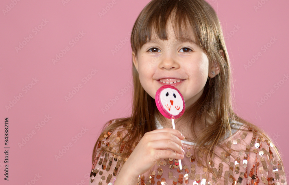 Young happy, smiled, pretty little girl with sweet lollypop candy. Standing in sequined dress Young happy, smiled, pretty little girl with sweet lollypop candy. Standing in sequined dress