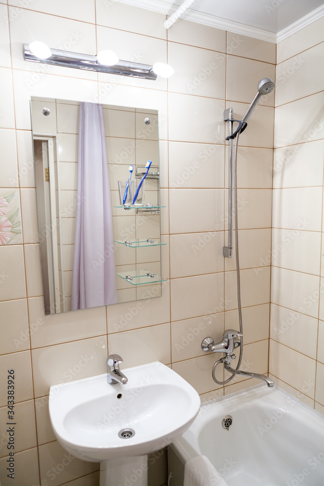 Interior of simple half bathroom with sink with mirror and bath with shower, white sanitary ware Interior of simple half bathroom with sink with mirror and bath with shower, white sanitary ware