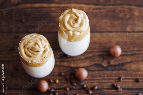 Top view of two beautiful glasses with dalgon on a wooden table surrounded by chocolates and coffee beans. Place for text photo