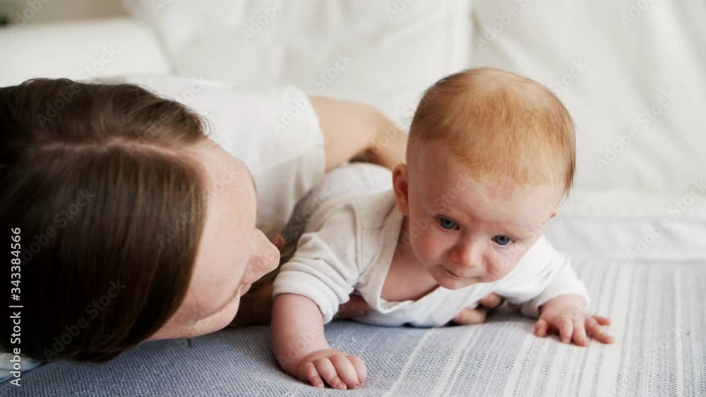 Happy mom posing with cute baby daughter, speaking and smiling. New mother nursing six month child at home. Baby care and parenthood concept