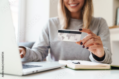 Cropped photo of woman using laptop while holding credit card
